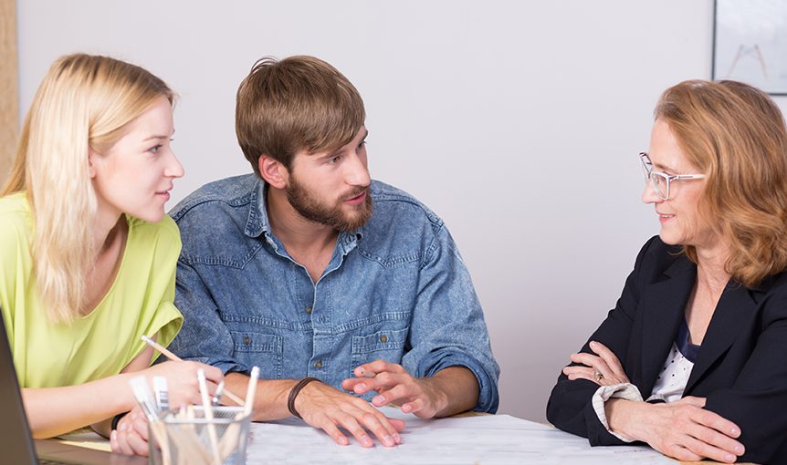 Eine junge Frau und ein junger Mann sind in einer Beratung mit einer Beraterin.