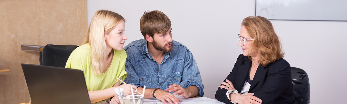 Eine junge Frau und ein junger Mann sind in einer Beratung mit einer Beraterin.