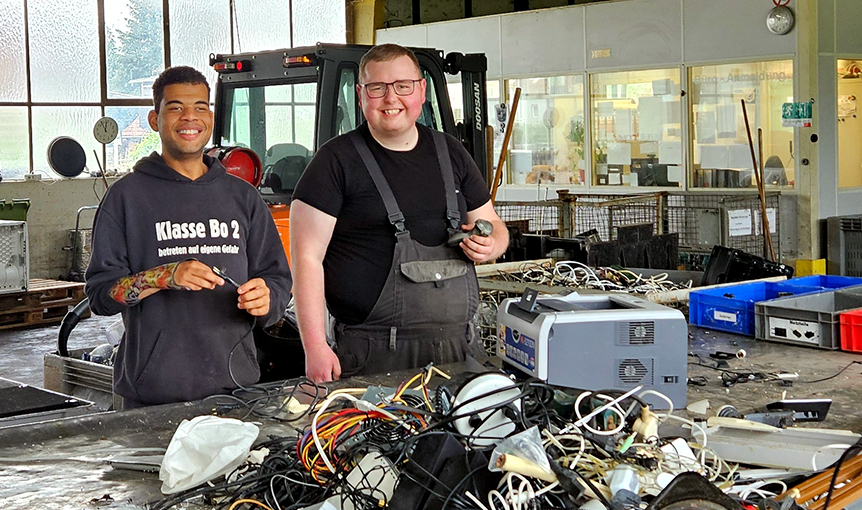 Zwei Männer arbeiten in der Elektro-Altgeräte-Entsorgungswerkstatt.