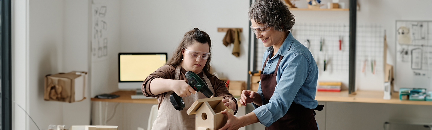 Zwei Frauen stehen in einer Schreinerei und bauen einen Nistkasten.