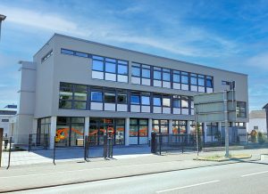 dreistöckiges graues Bürogebäude mit vielen Fenstern
